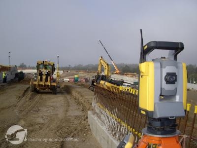 Total station guides the pavement trim while the batter is trimmed using GPS.